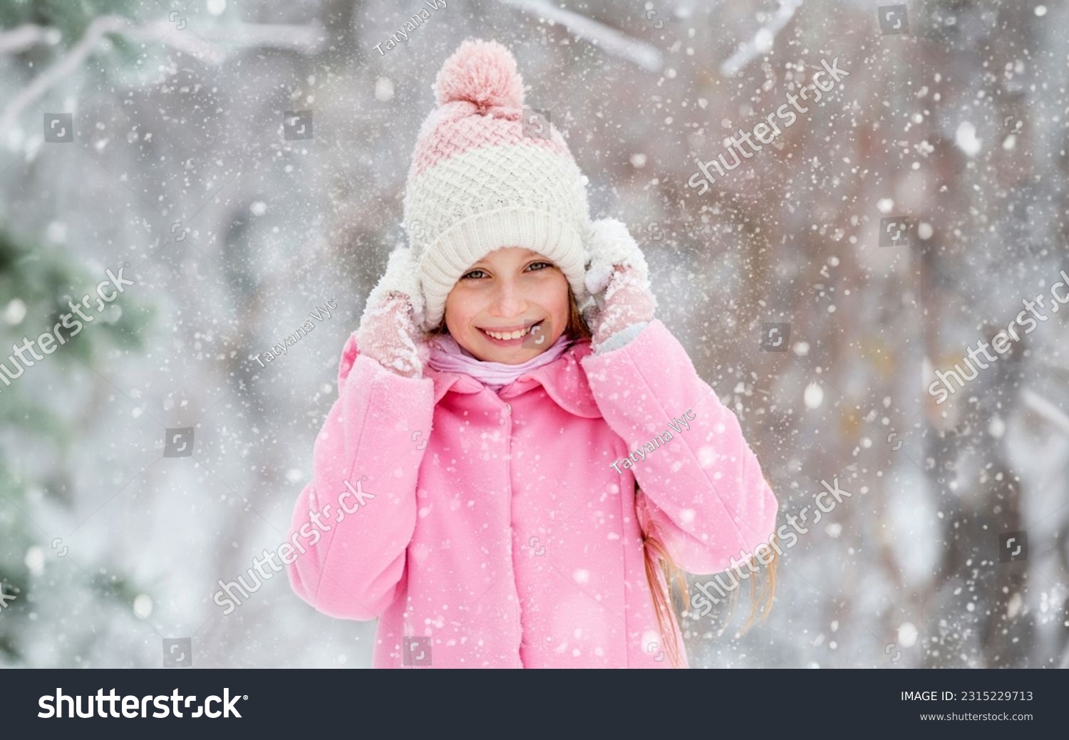 Lovely girl grinning widely and happily in the winter forest, holding her hat #2315229713