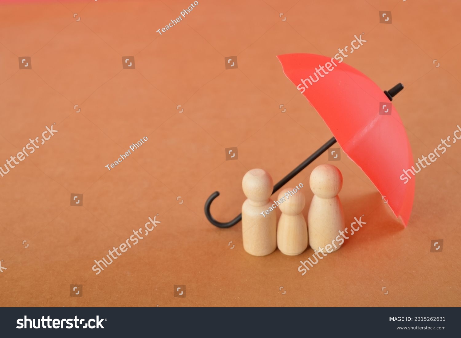 Red toy umbrella and wooden doll figures isolated on a brown background. Insurance coverage concept. #2315262631