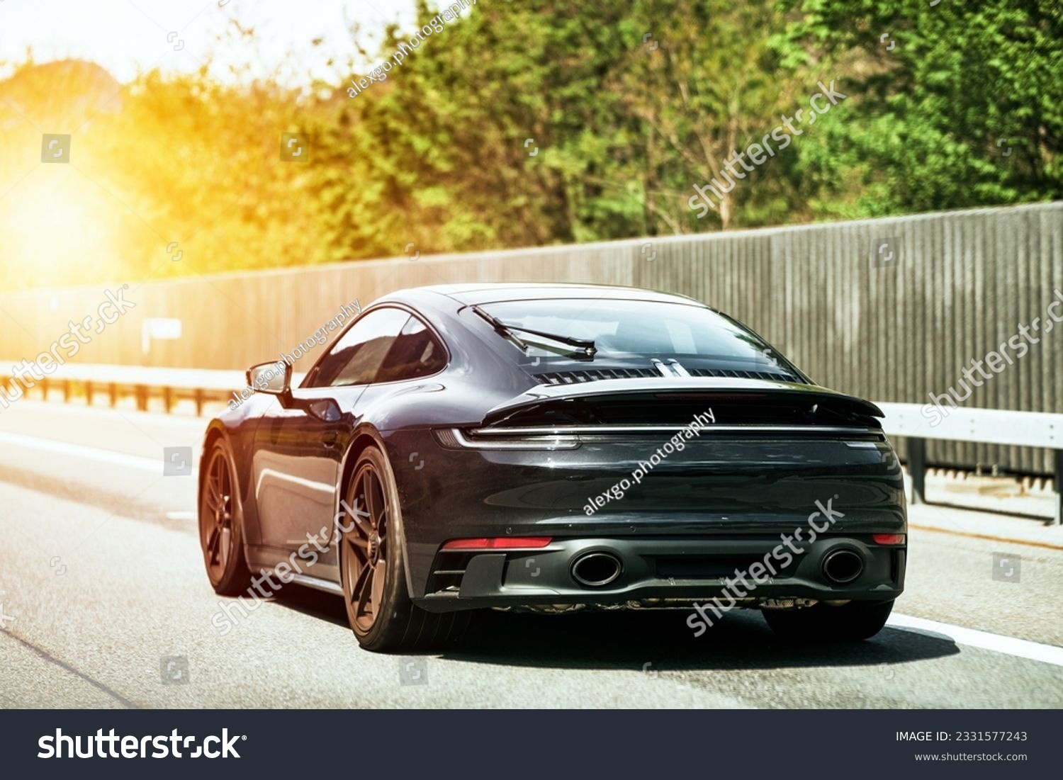 Sleek Black German Roadster. Brand New Luxury Carrera Sports Car on the Highway. Rear view of the 911 GTS sports car. #2331577243
