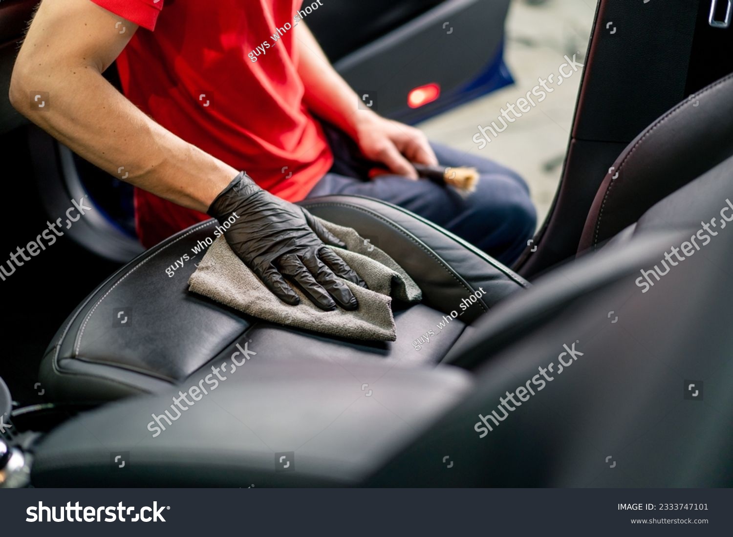 Detailing a man an employee of a car service station performs chemical cleaning and washing of a car with microfiber cloth #2333747101