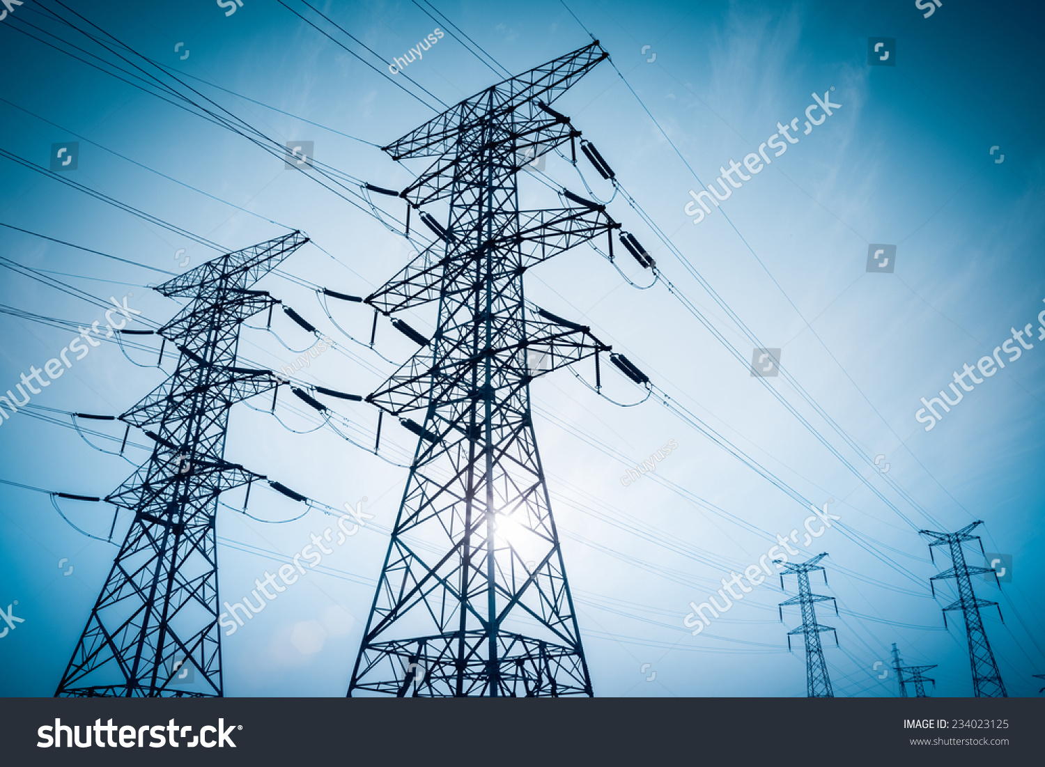electricity transmission pylon silhouetted against blue sky at dusk  #234023125