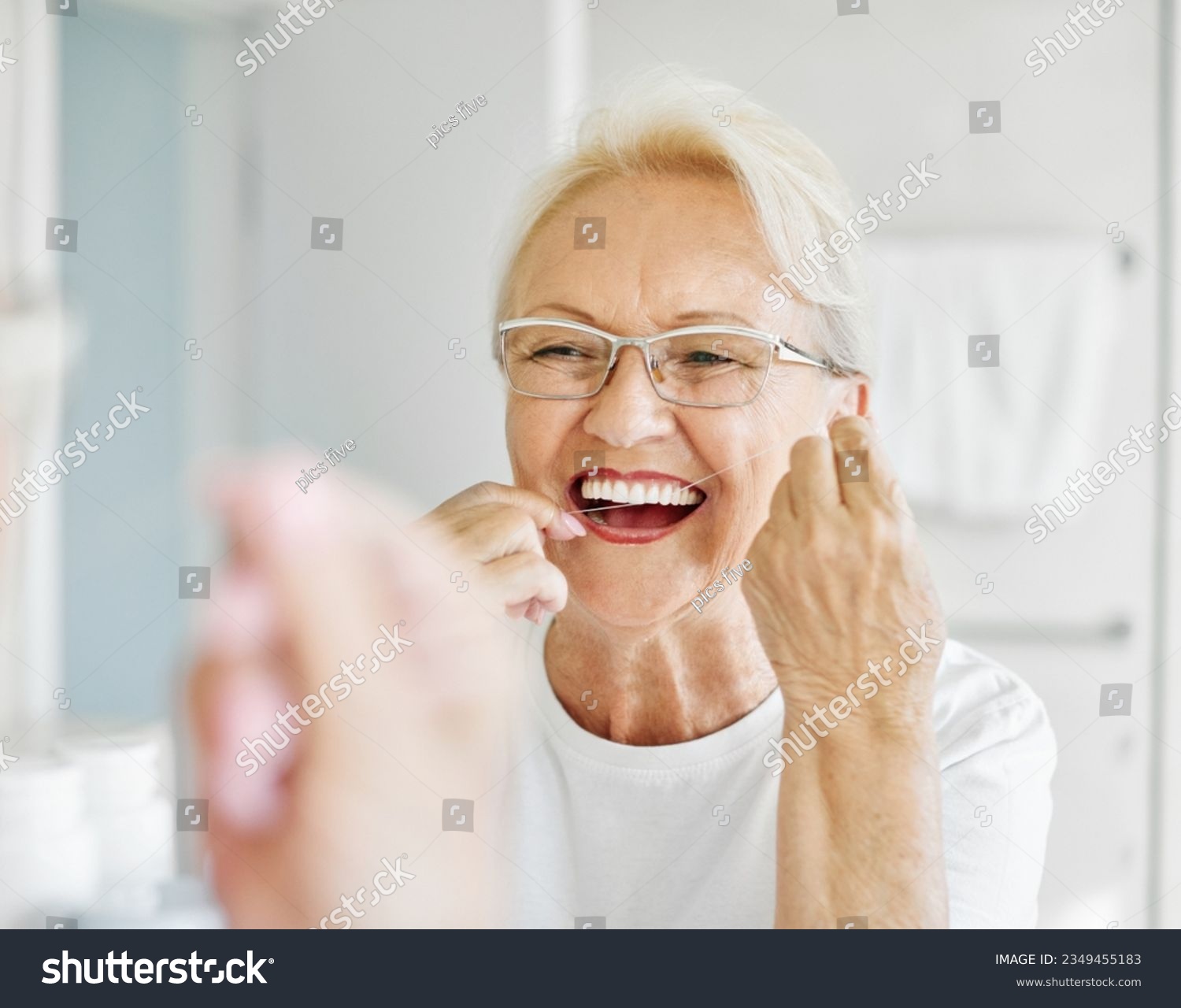 Portrait of an elderly senior woman is cleaning brushing his teeth using dental floss in front of mirror in bathroom. Dental hygiene, vitality and beauty concepts #2349455183