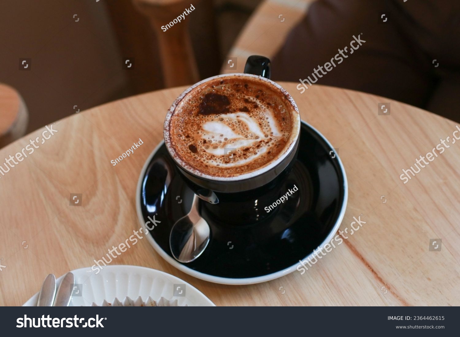 Hot coffee with latte art in black  ceramic cup on wooden table. Cappuccino or latte with frothy foam milk. Cafe and bar, barista art concept. #2364462615