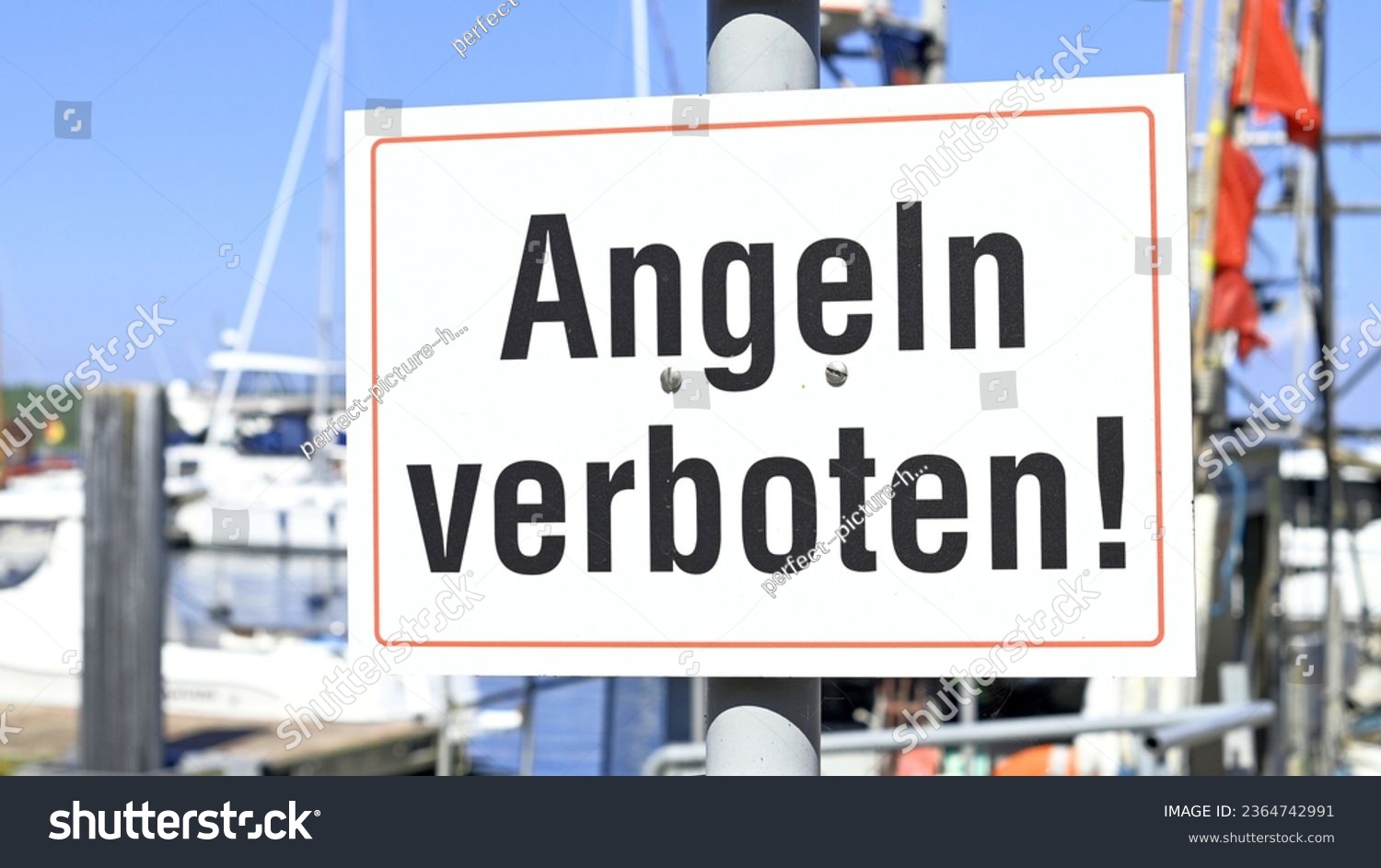 Close-up of a sign in the sunshine in a harbor on No Fishing! is written in German script #2364742991