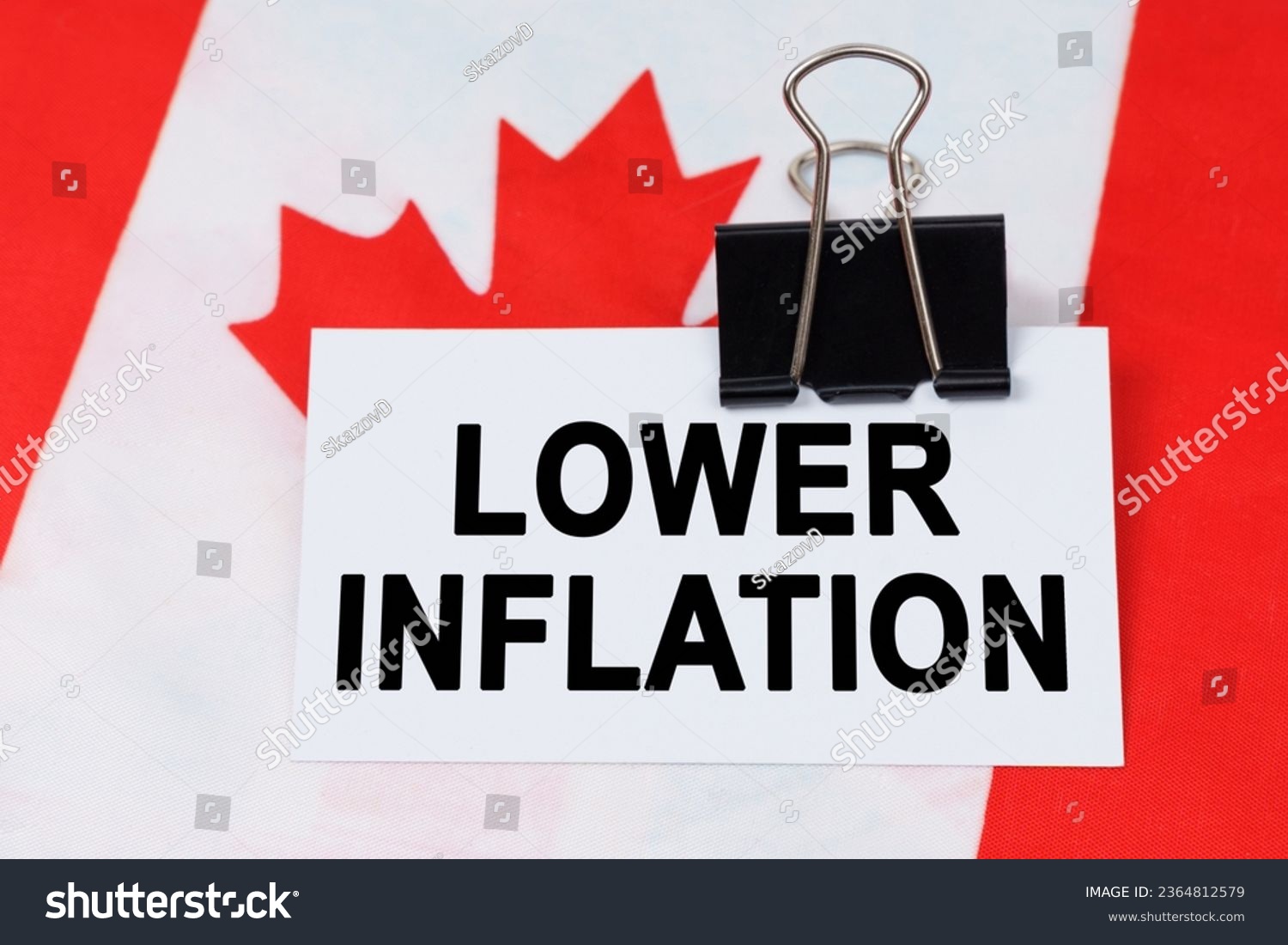 Economy and finance concept. On the flag of Canada lies a business card with the inscription - lower inflation. #2364812579