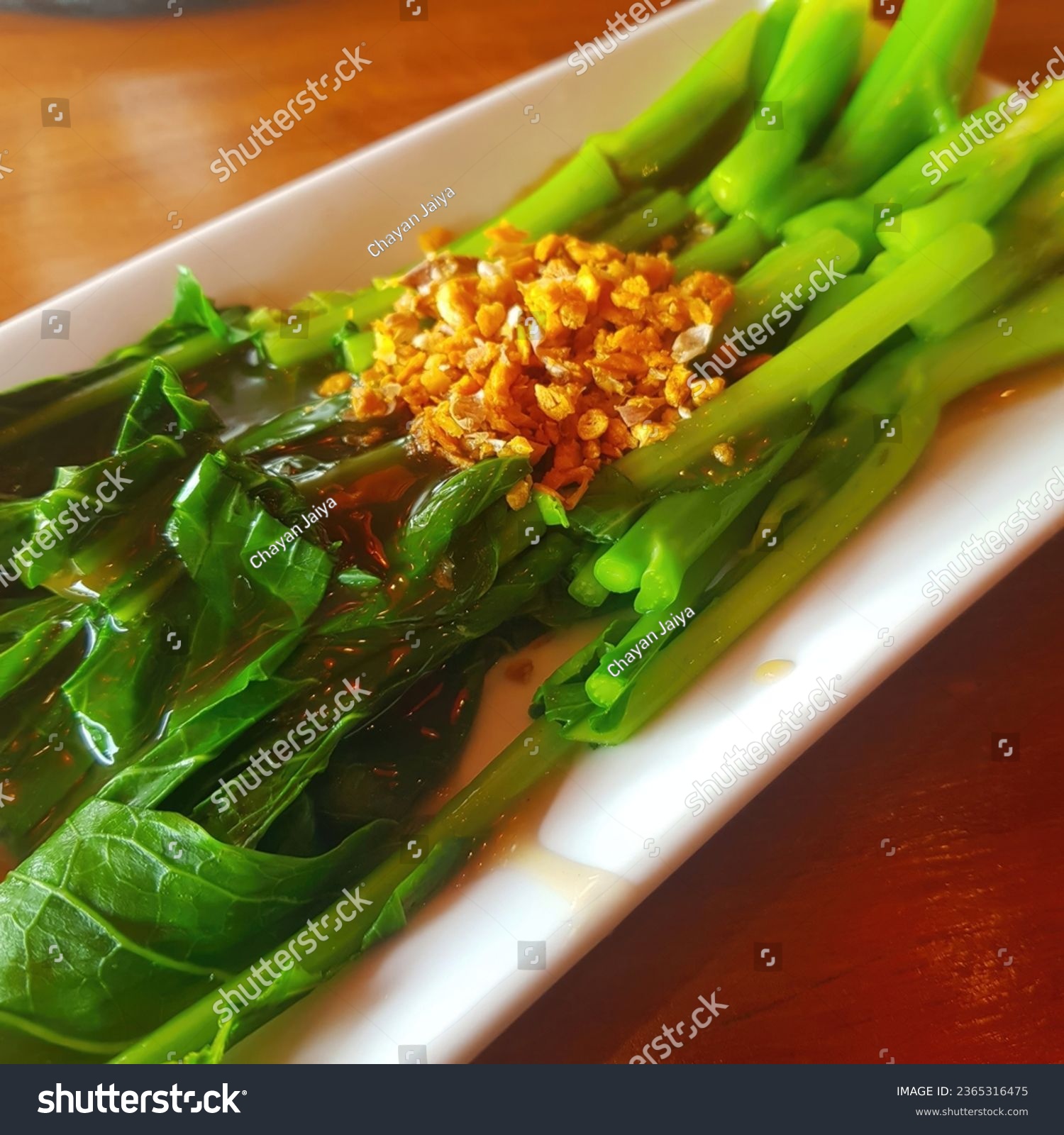 Chinese fried kale with garlic in white plate on wooden table. #2365316475