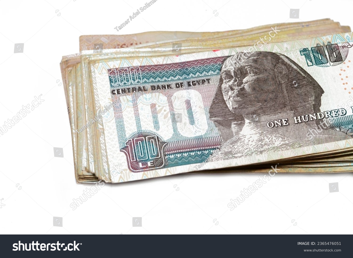Stack of Egyptian currency of 100 EGP LE one hundred Egyptian pound bills, spending, giving and using money concept, paying and buying using banknotes with Sultan Hassan mosque and the Sphinx #2365476051