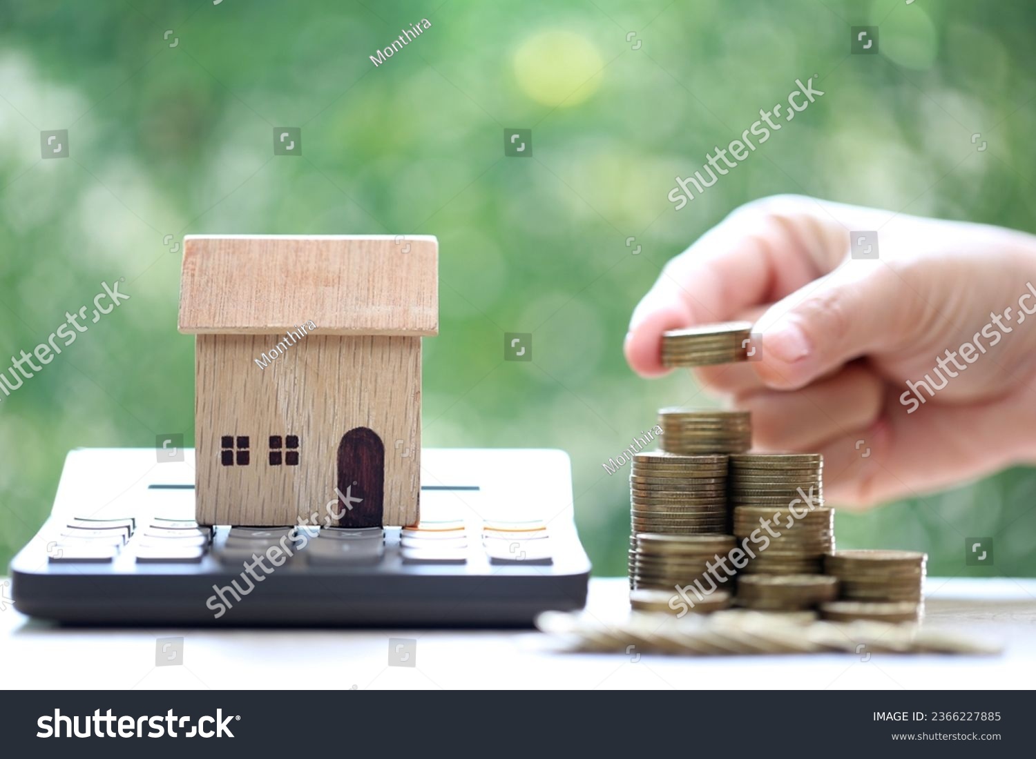 Calculating interest payments, Model house on calculator and stack of coins money on natural green background,Business investment and real estate concept #2366227885