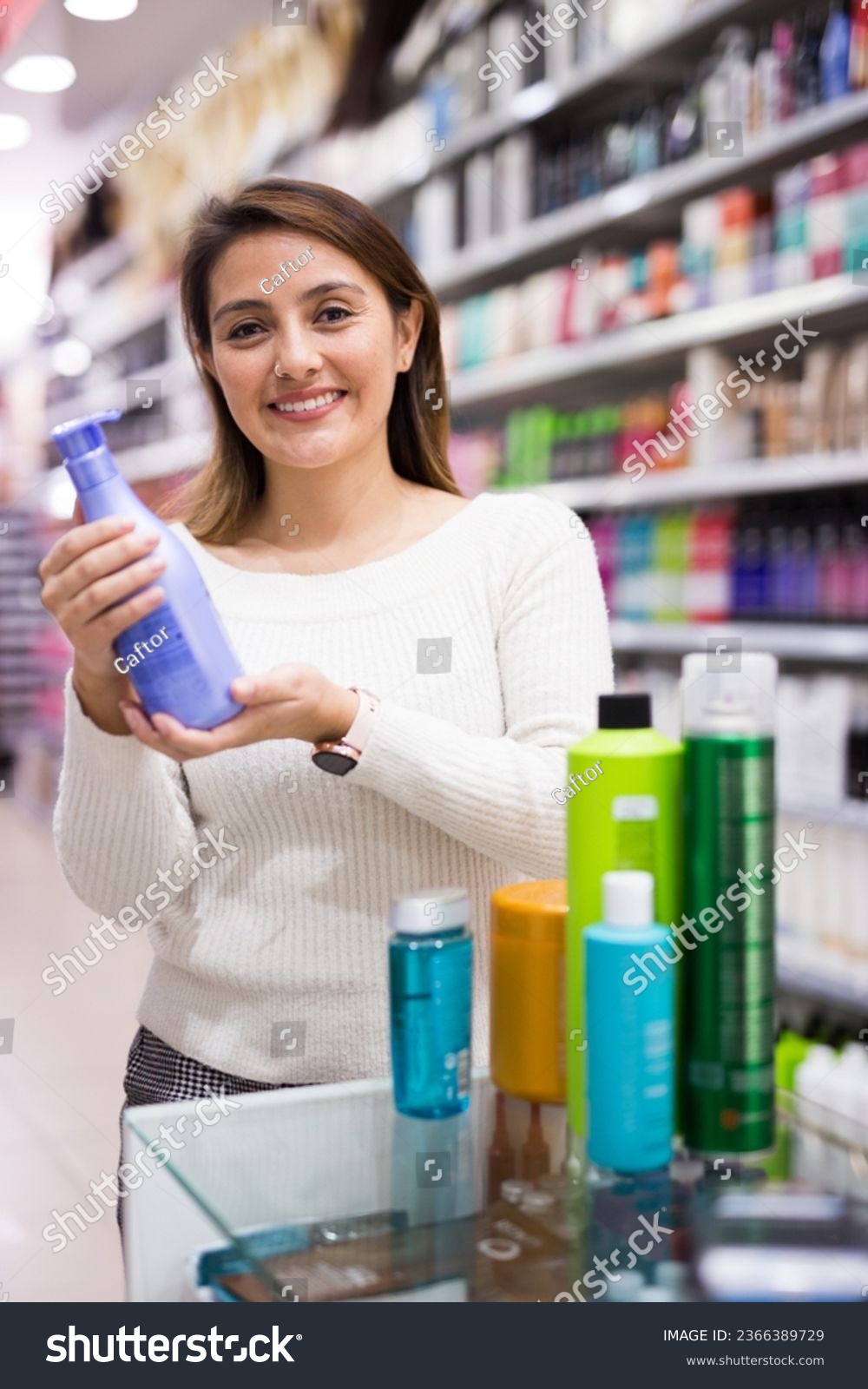 Positive young woman looking for haircare products #2366389729