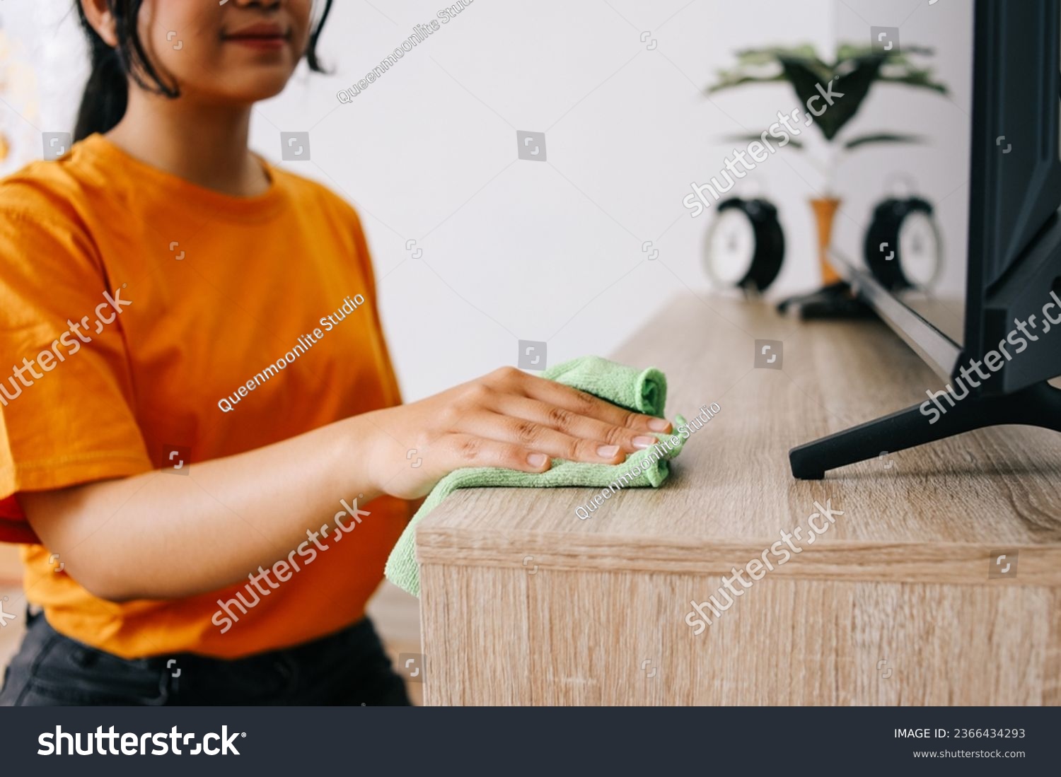 Young Asian woman cleaning and wiping the cabinet tv with microfiber cloth in living room #2366434293