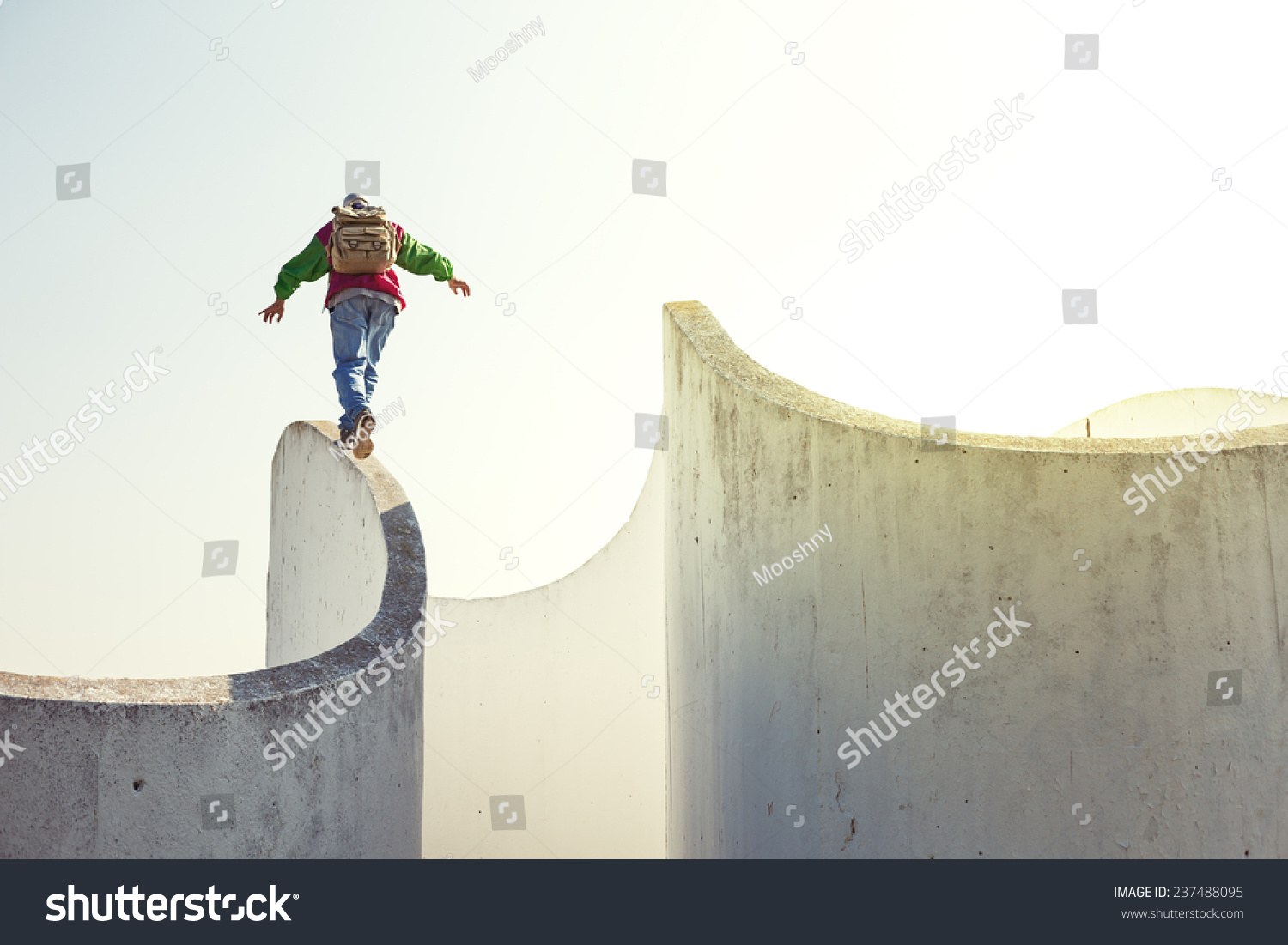 brave extreme man with backpack walking on a thin concrete wall #237488095