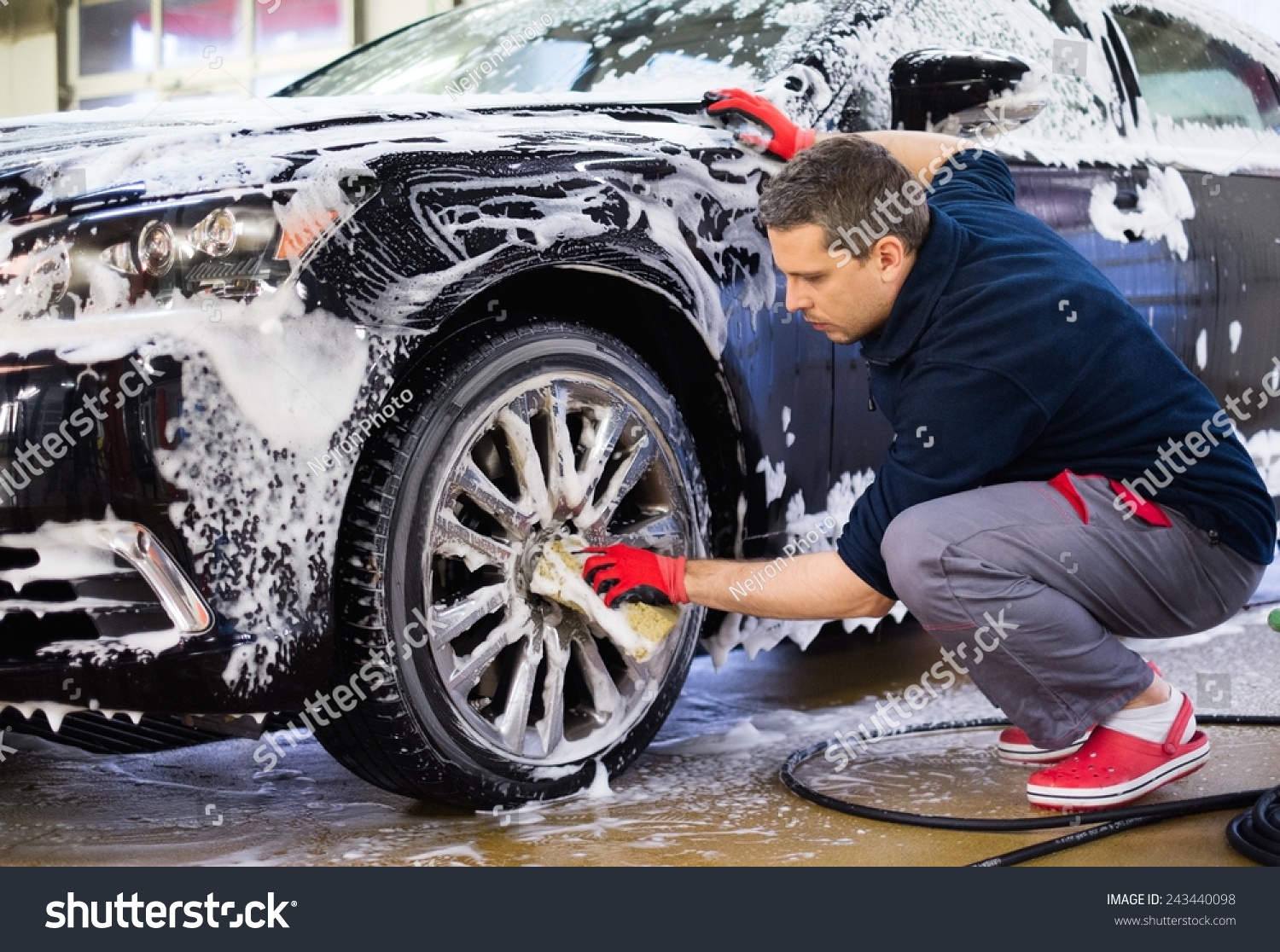 Man worker washing car's alloy wheels on a car wash  #243440098