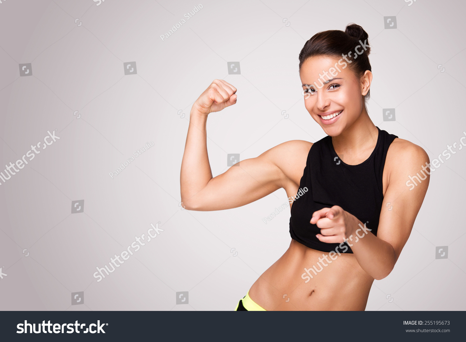 Cheerfully smiling mixed race sporty woman demonstrating biceps, isolated on white background #255195673