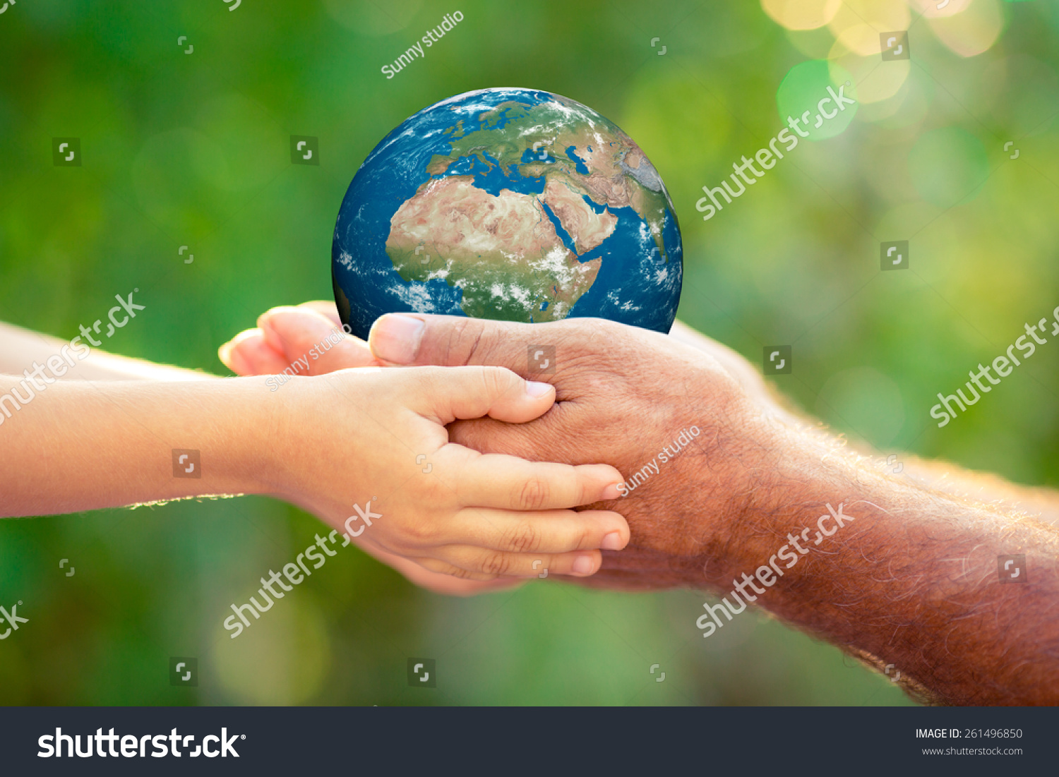 Child and senior holding planet in hands against green spring background. Earth day holiday concept. Elements of this image furnished by NASA #261496850