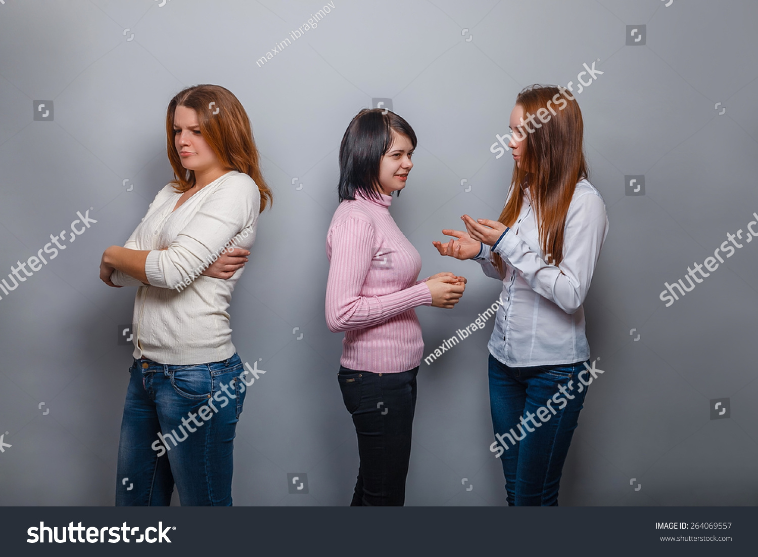 Two girls talking  blonde  European appearance and ignore the third girl on a gray background, resentment, sadness conflict friend #264069557