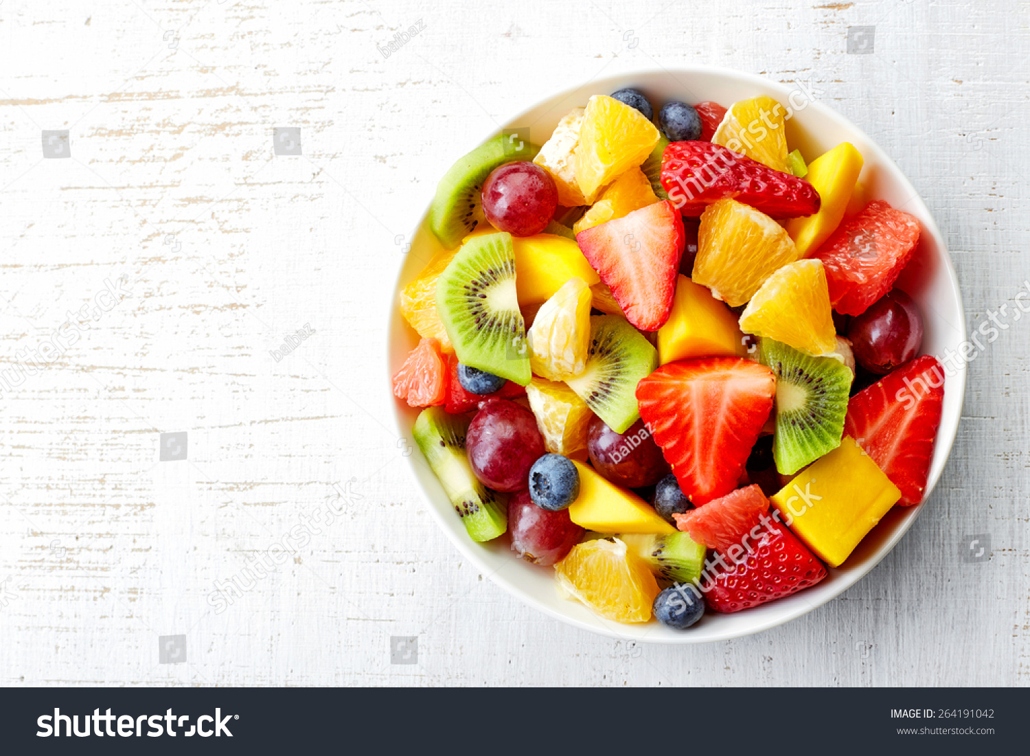 Bowl of healthy fresh fruit salad on wooden background. Top view. #264191042