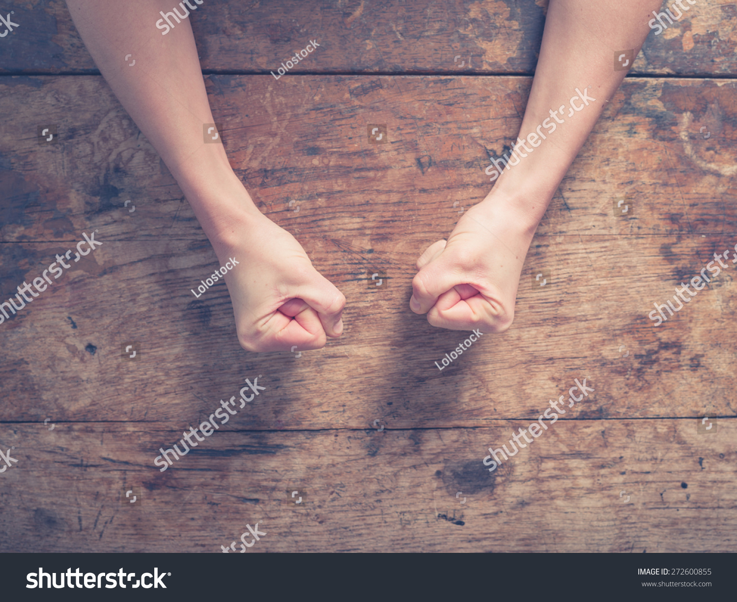 Female fists clenched on a wooden table in anger #272600855