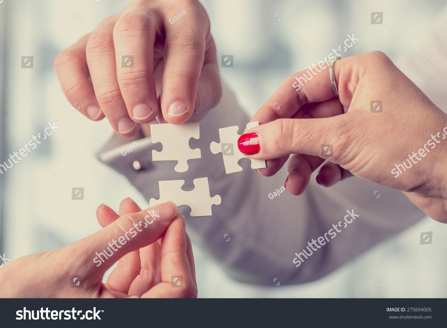 Hands of different people matching together three complementary puzzle pieces, concept of unity and problem solving, close-up with retro filter effect. #275694005