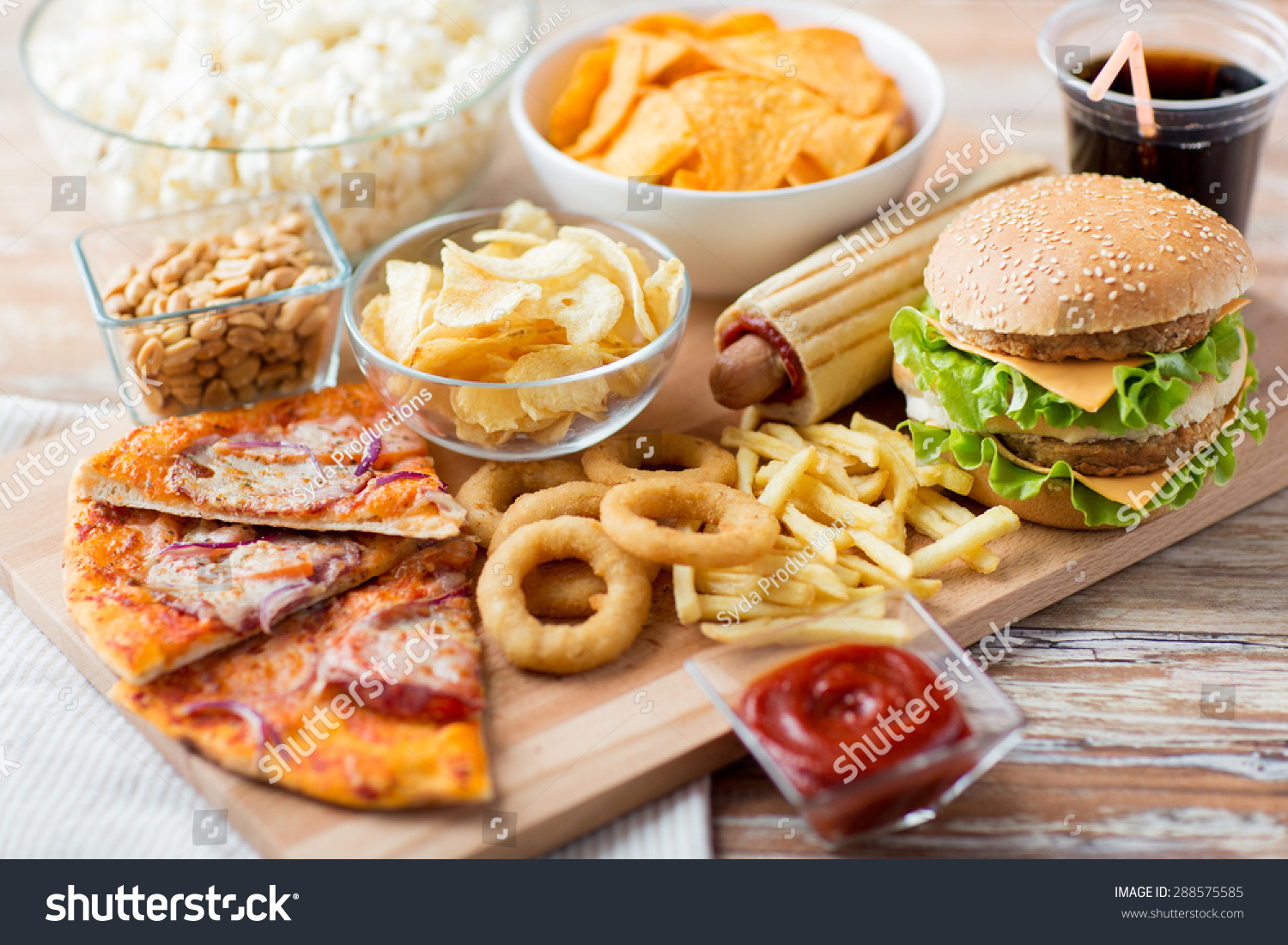 fast food and unhealthy eating concept - close up of fast food snacks and cola drink on wooden table #288575585