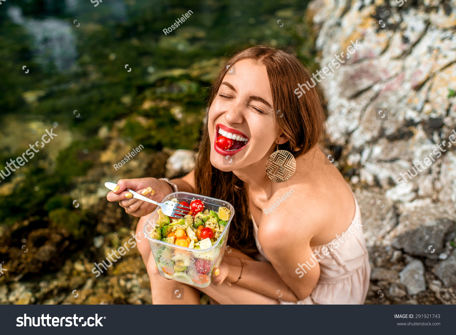 Woman eating healthy salad from plastic container near the river #291921743