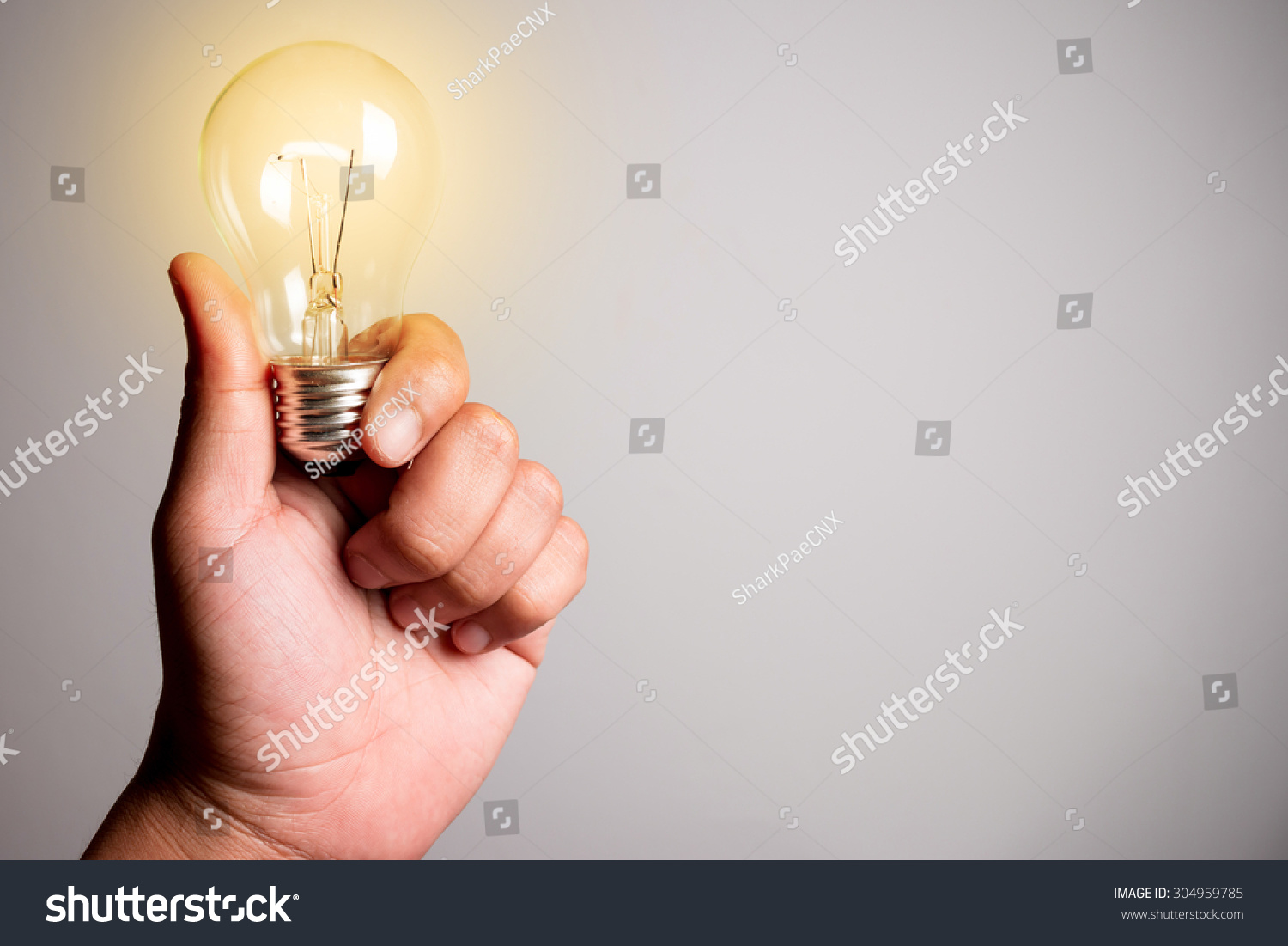 Hand holding a glowing light bulb #304959785