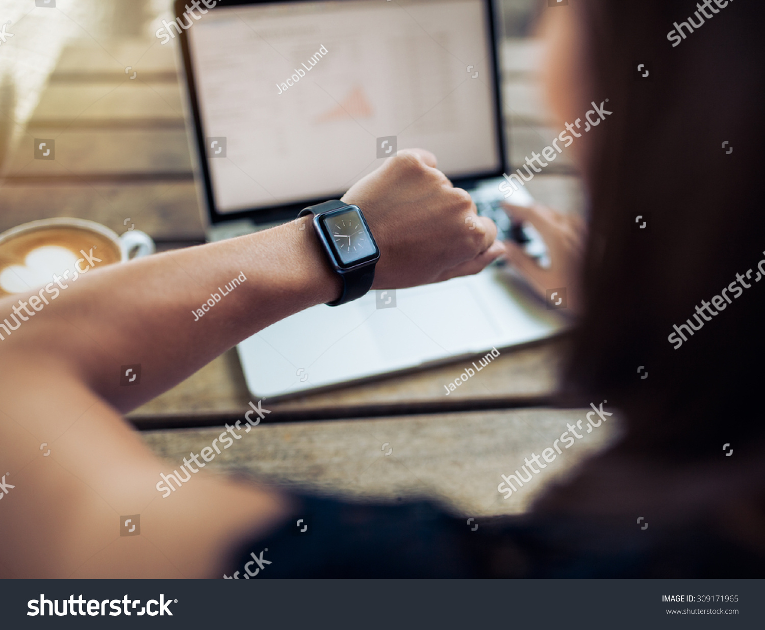 Close up shot of a woman checking time on her smartwatch. Female sitting in cafe with a laptop and cup of coffee. #309171965