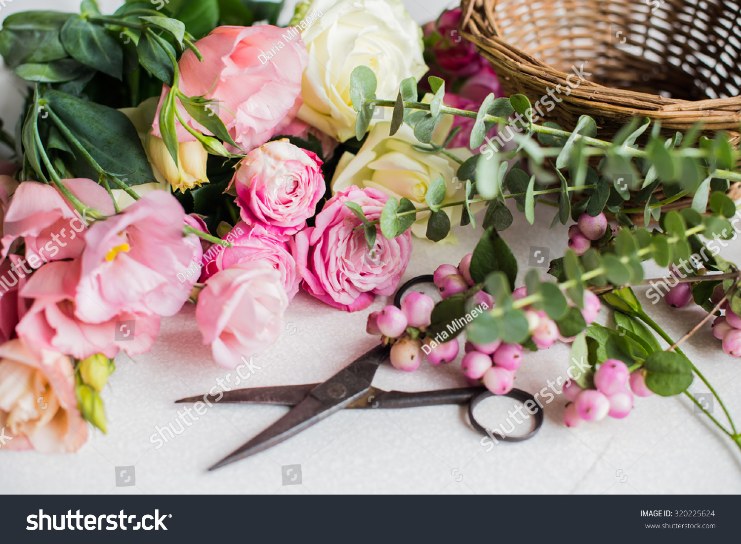 Fresh flowers, leaves, and tools to create a bouquet on a table, florist's workplace. #320225624