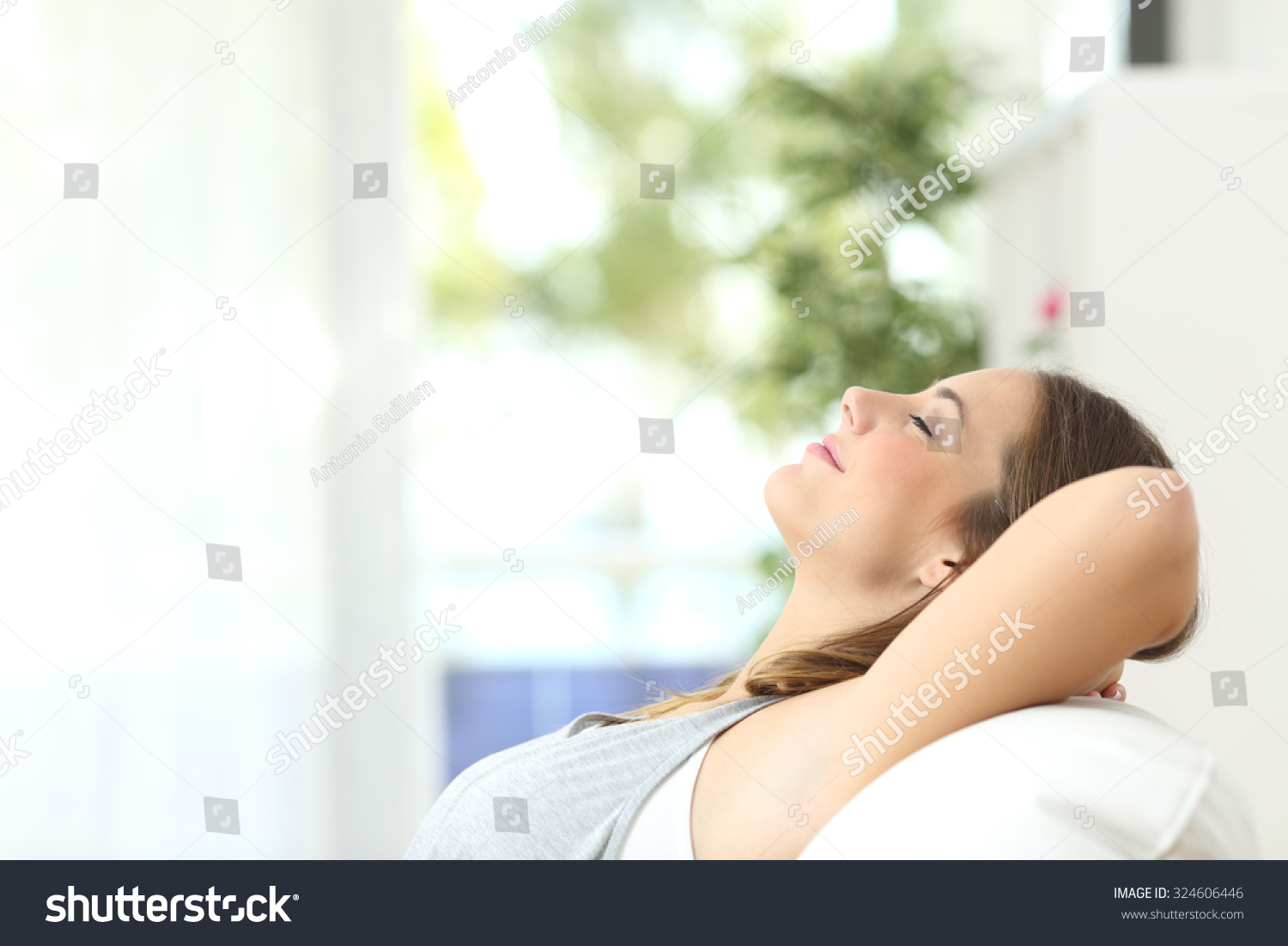 Profile of a beautiful woman relaxing lying on a couch at home #324606446