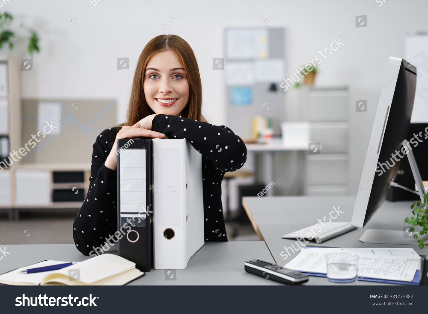 relaxed businesswoman leaning on black and white folders #331774382