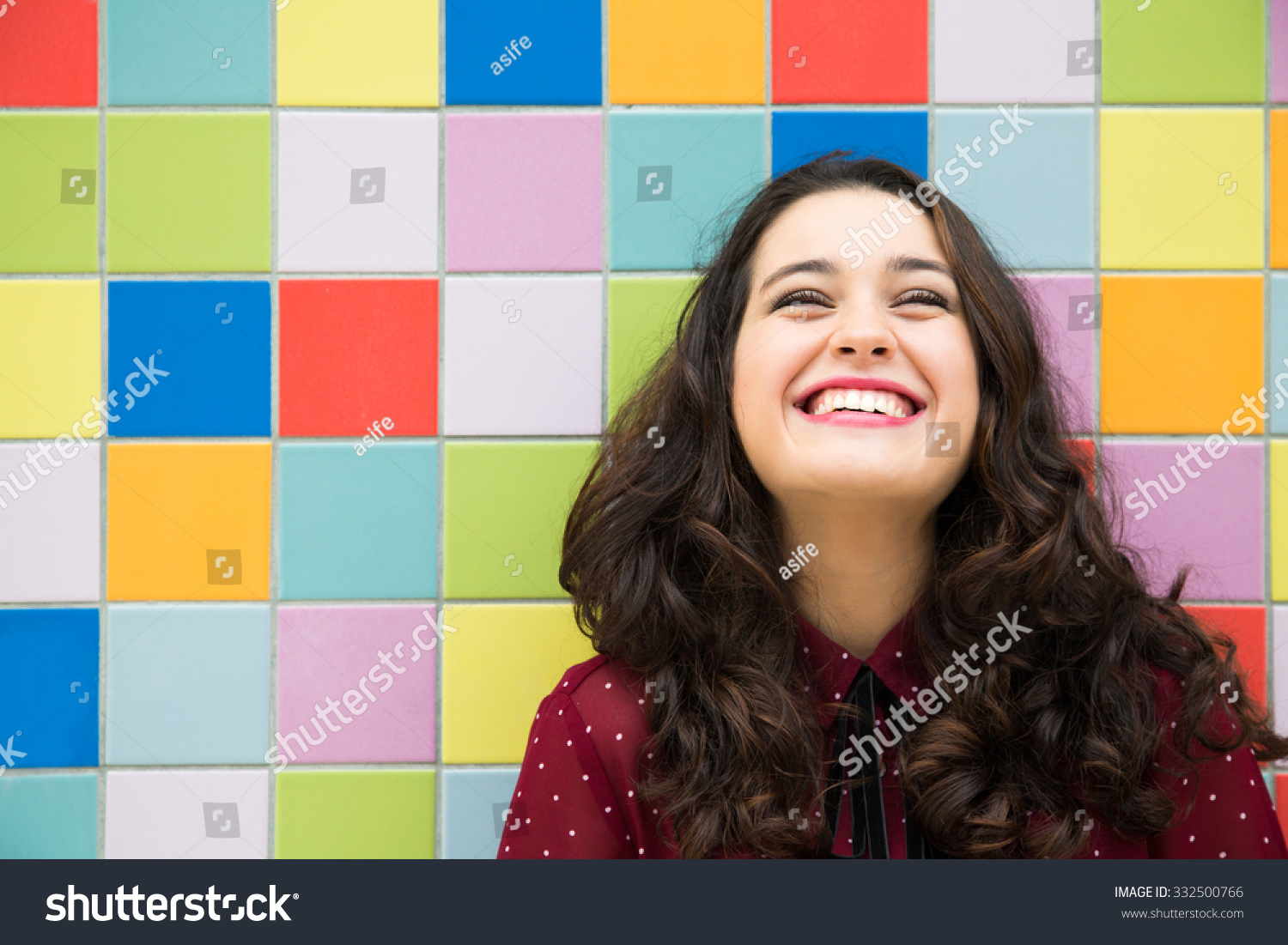 Happy girl laughing against a colorful tiles background. Concept of joy #332500766