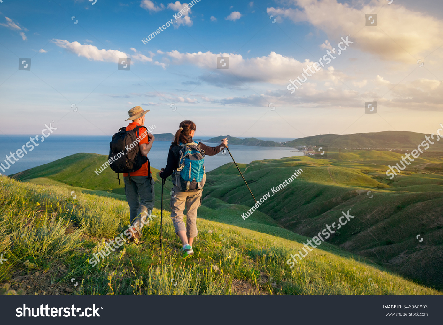 Young couple hike in the mountains. A man and a woman walking and looking at the beautiful landscape. #348960803