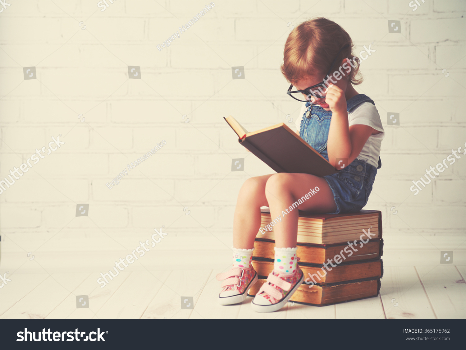happy child little girl with glasses reading a books #365175962