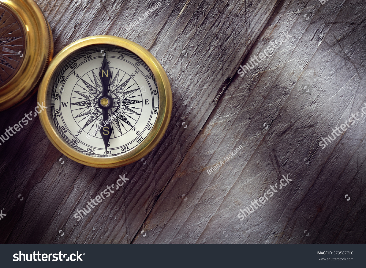 Antique golden compass on wood background concept for direction, travel, guidance or assistance #379587700