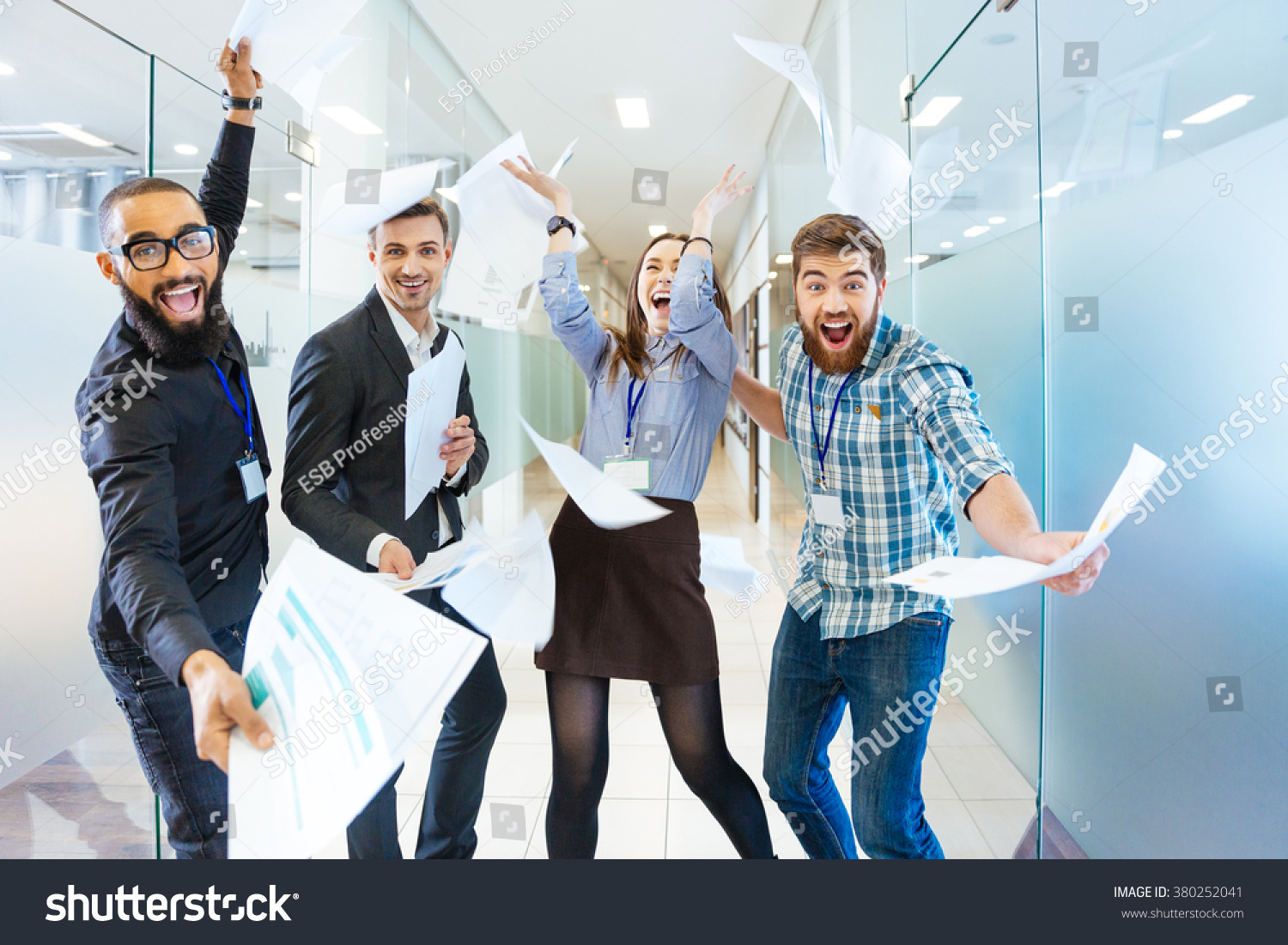 Group of joyful excited business people throwing papers and having fun in office #380252041