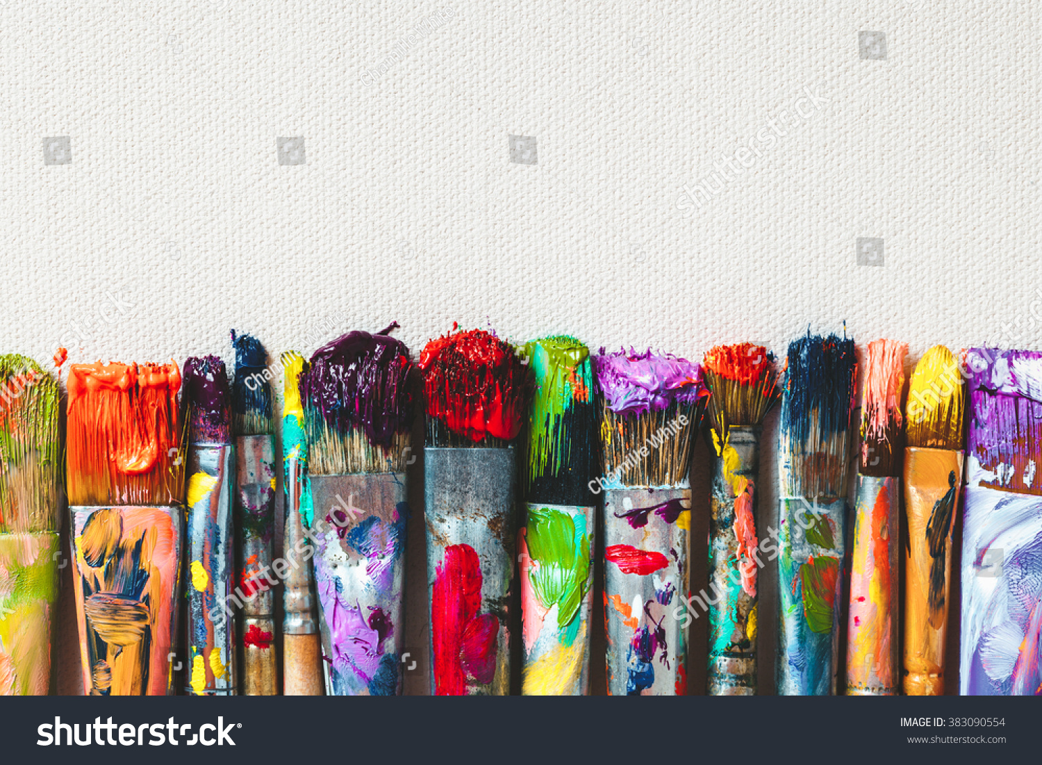 Row of artist paintbrushes closeup on artistic canvas. #383090554