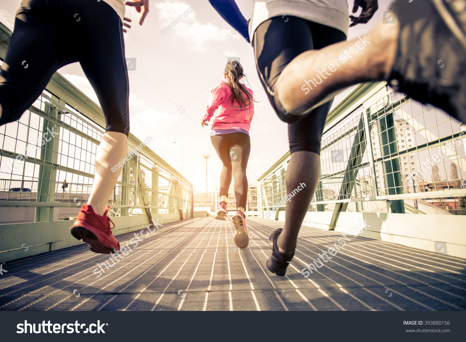 Three runners sprinting outdoors - Sportive people training in a urban area, healthy lifestyle and sport concepts #393880156