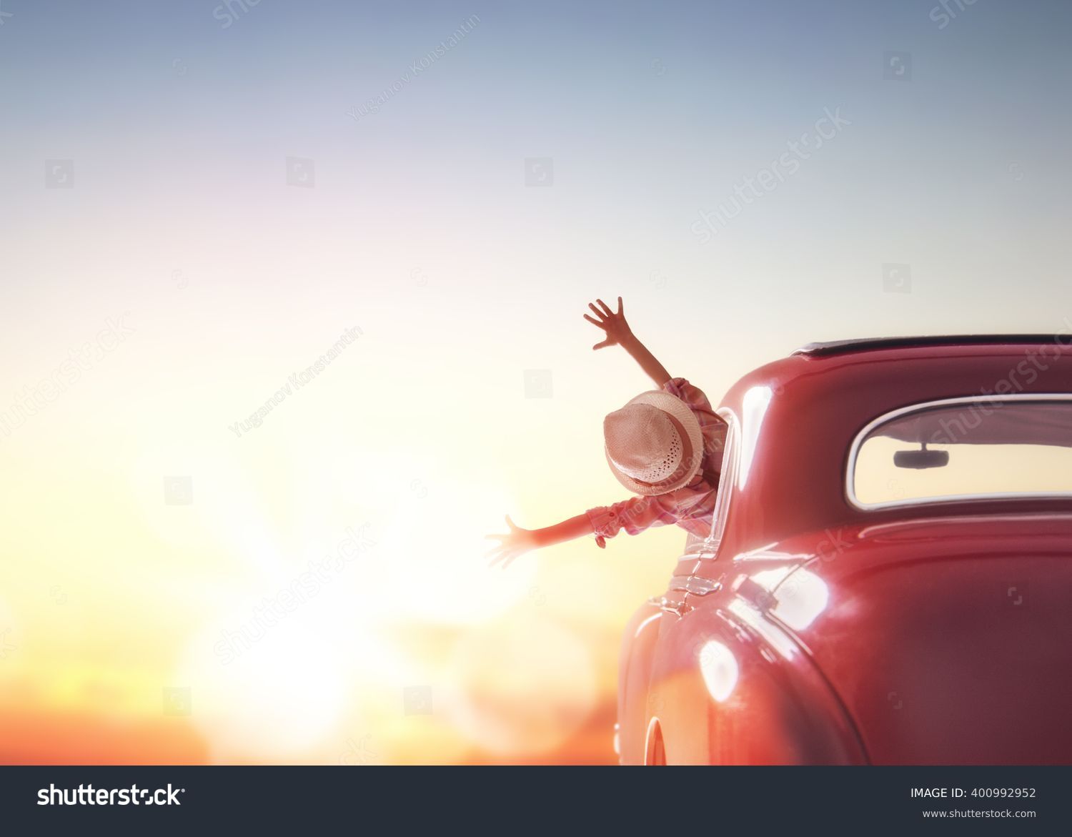 Toward adventure! Girl relaxing and enjoying road trip. Happy girl rides into the sunset in vintage car. #400992952