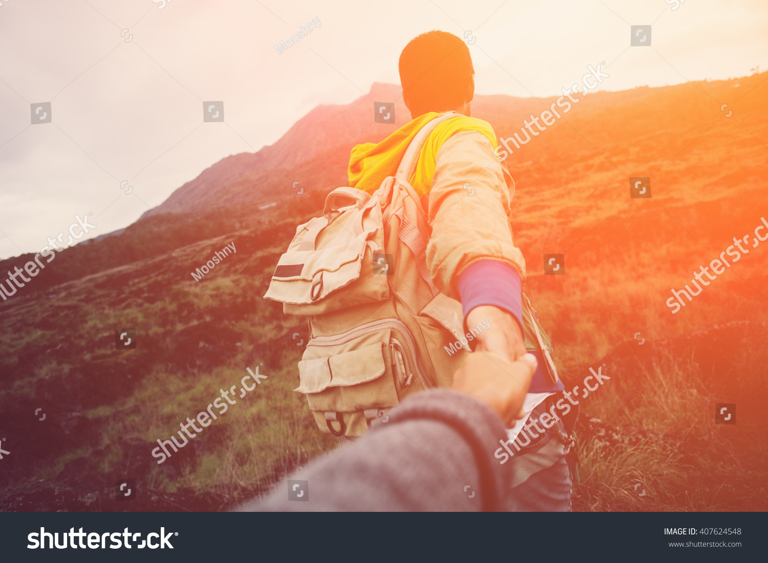 Brave and romantic traveler guiding woman to the mountain in the wild (intentional sun glare and vintage color) #407624548