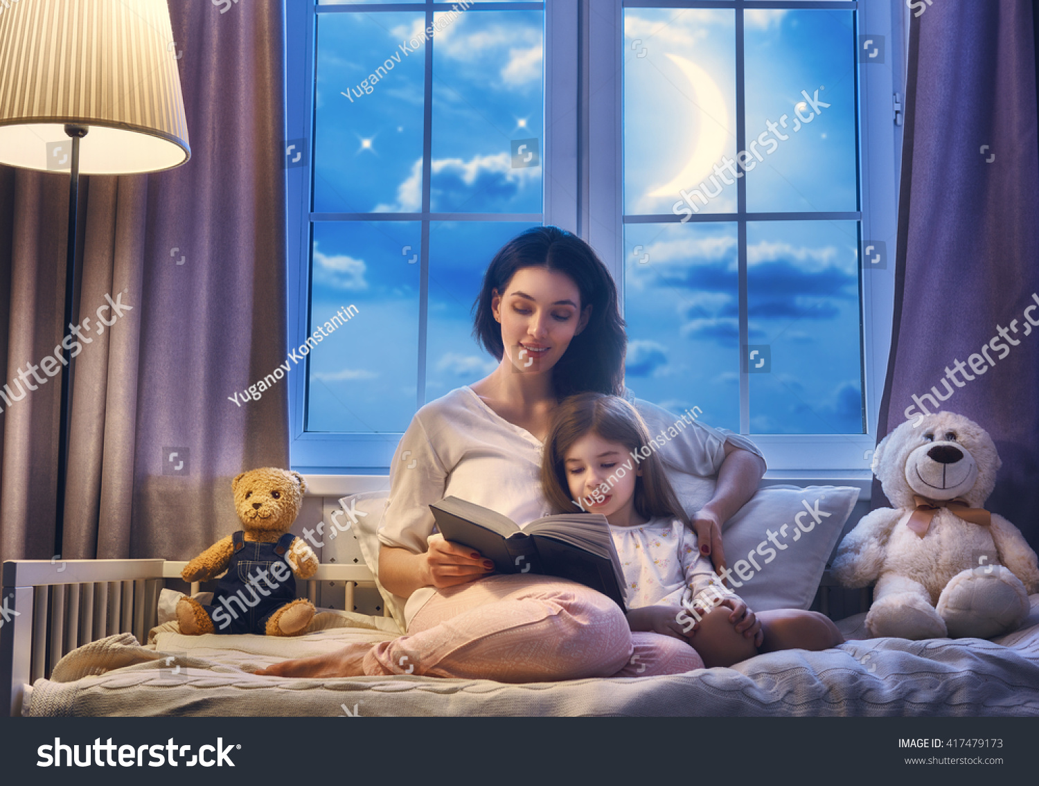 Family reading bedtime. Pretty young mother reading a book to her daughter. #417479173