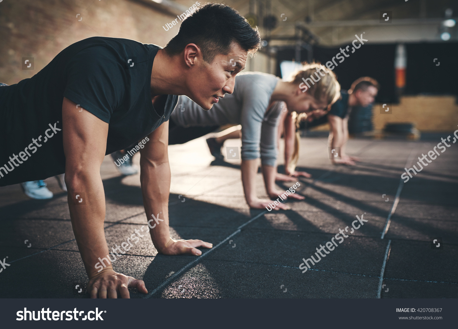 Fit young people doing pushups in a gym looking focused #420708367