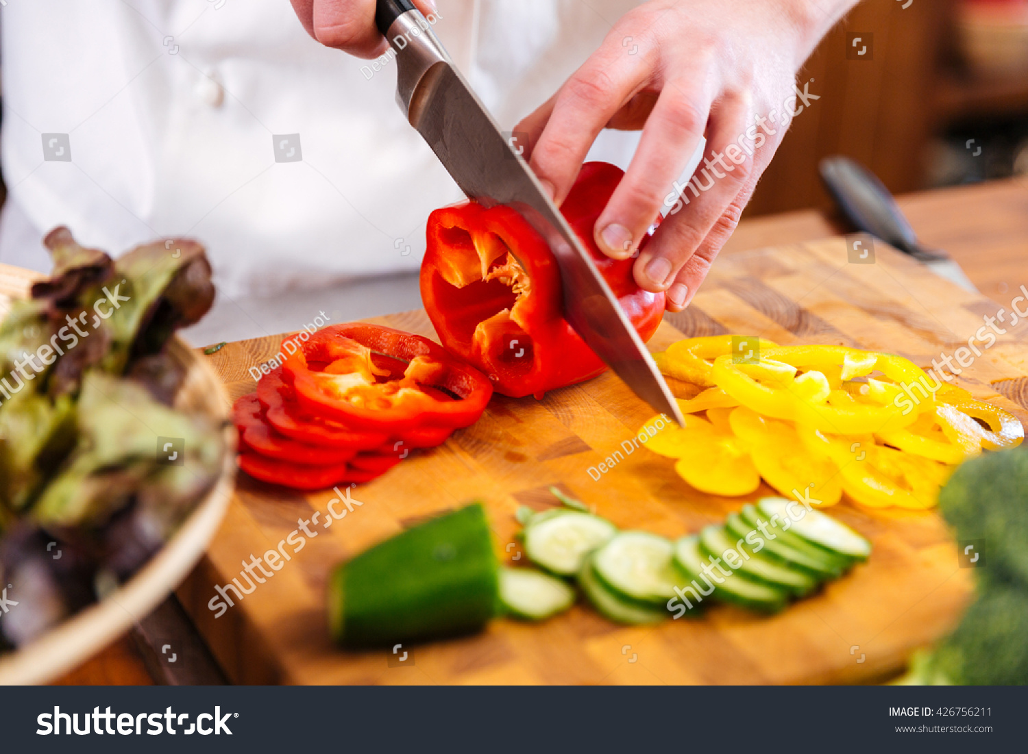 Closeup of hands of chef cook cutting vegetables on wooden table  #426756211