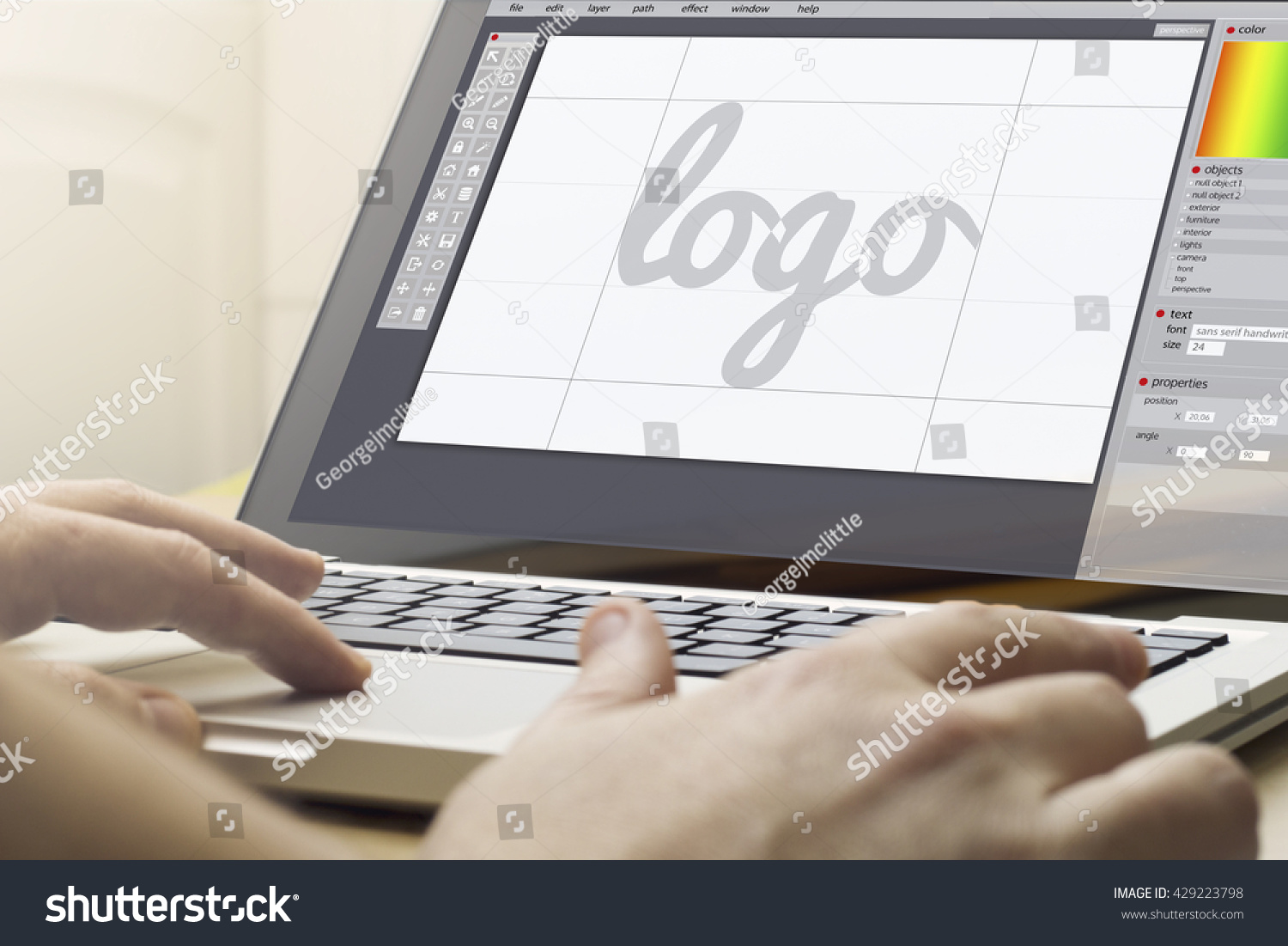 logo design concept: man using a laptop with logo design software on the screen. Screen graphics are made up. #429223798