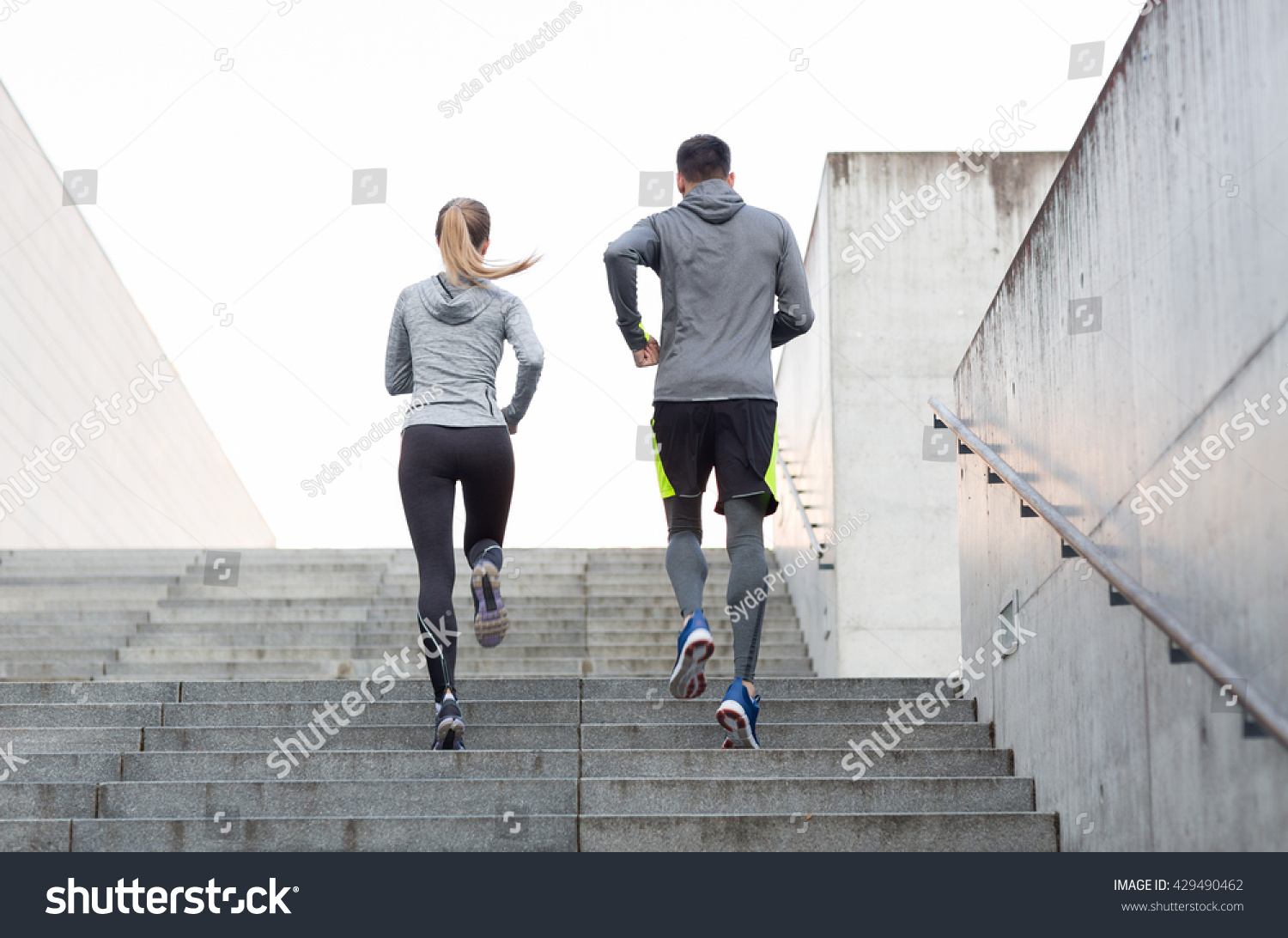 fitness, sport, people, exercising and lifestyle concept - couple running upstairs on city stairs #429490462