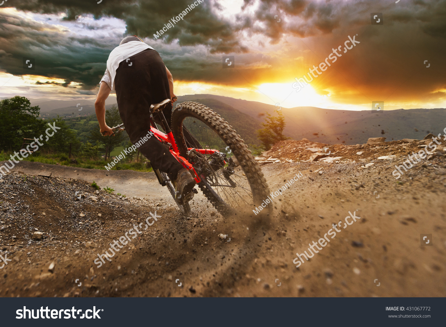 Man on mountain bike rides on the trail on a stormy sunset. #431067772