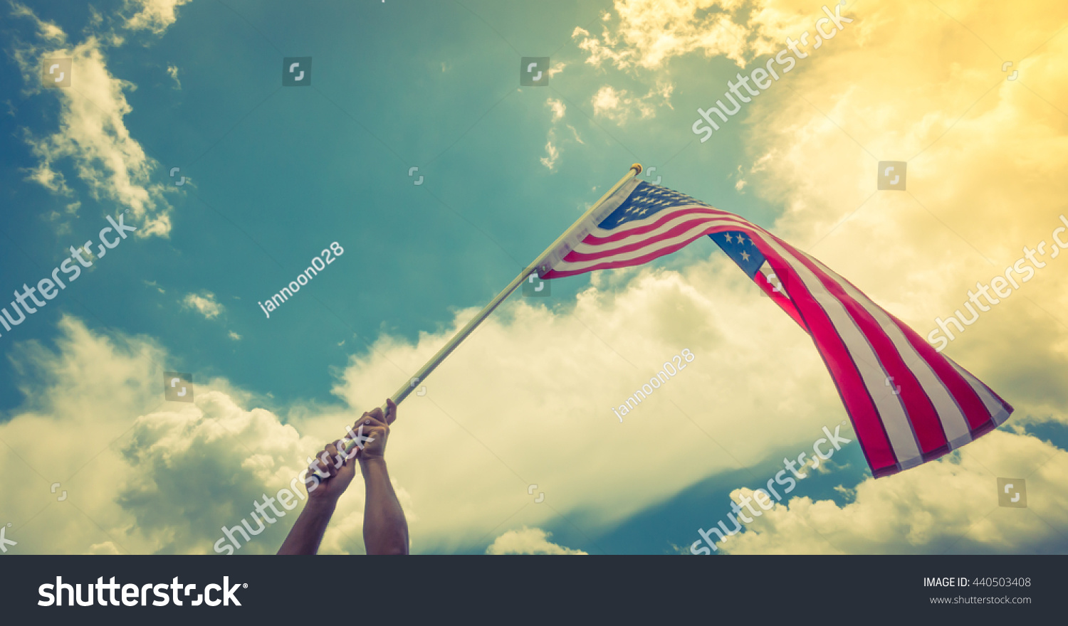 American flag with stars and stripes hold with hands against blue sky ( Filtered image processed vintage effect. ) #440503408