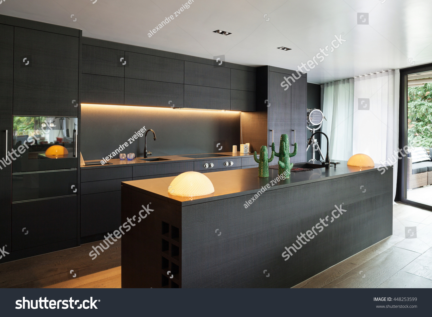Modern kitchen with black furniture and wooden floor #448253599