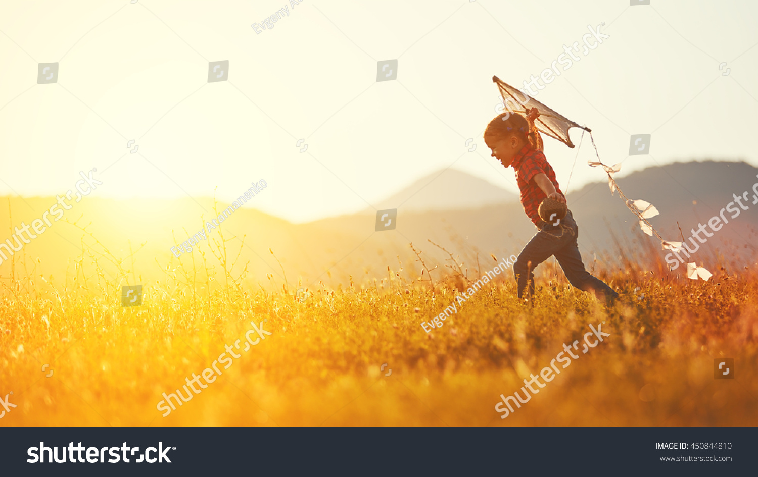 happy child girl with a kite running on meadow in summer in nature #450844810