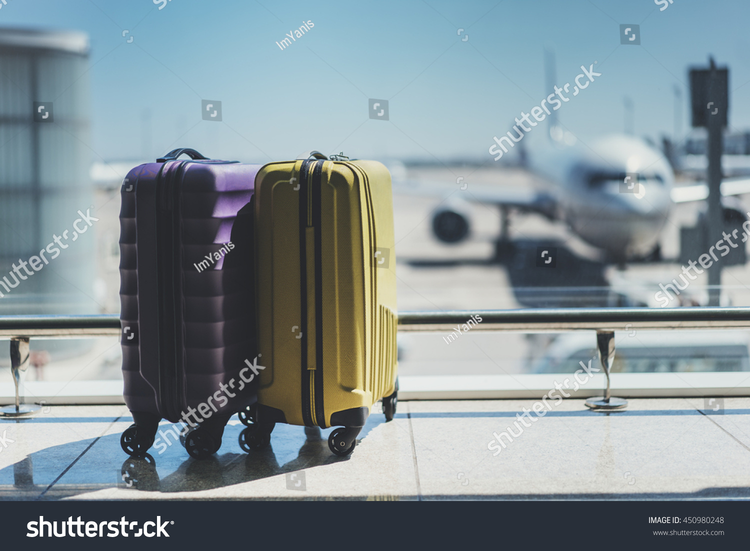 Suitcases in airport departure lounge, airplane in background, summer vacation concept, traveler suitcases in airport terminal waiting area, empty hall interior with large windows, focus on suitcases #450980248