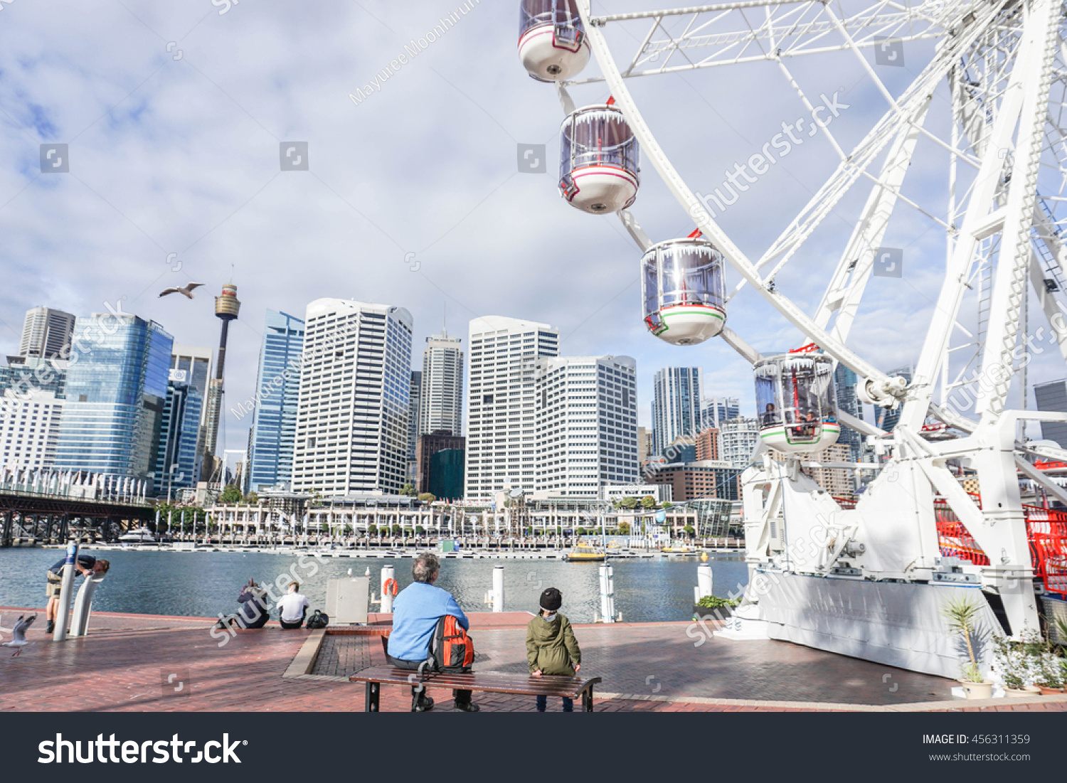 People enjoy sitting at the Darling Harbour with part of Ferris Wheel #456311359