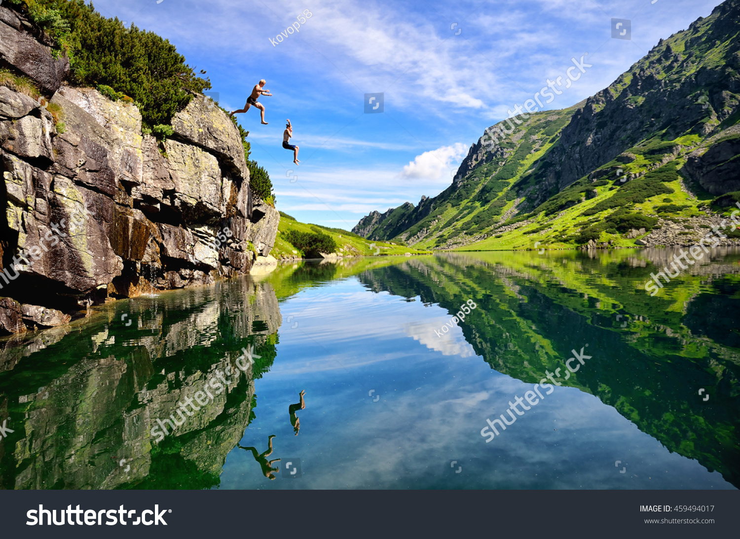Young couple jump together into lake in mountains with beautiful blue water and reflexion.  #459494017